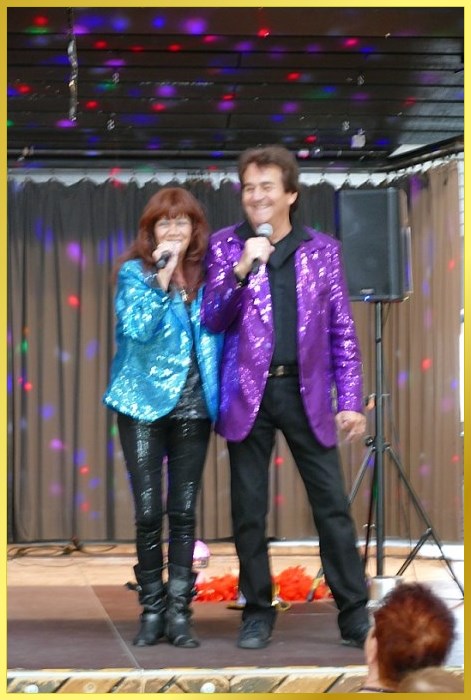 Gesangsduo mit Mikrofonen und lachen ins Publikum.