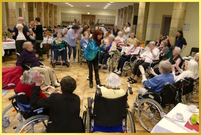 Umringt von Rollstuhlfahrern singt die Schlagerpiratin Lieder zum mitsingen.