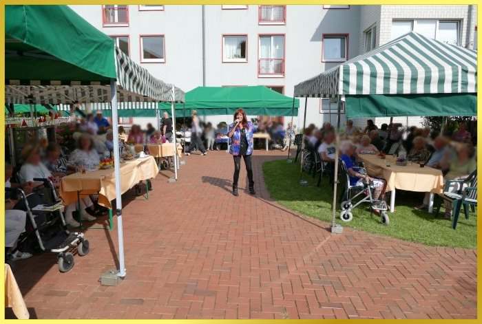 Publkum sitzt in kleinen Zelten. Schlagerpiratin steht in der Sonne uns singt!