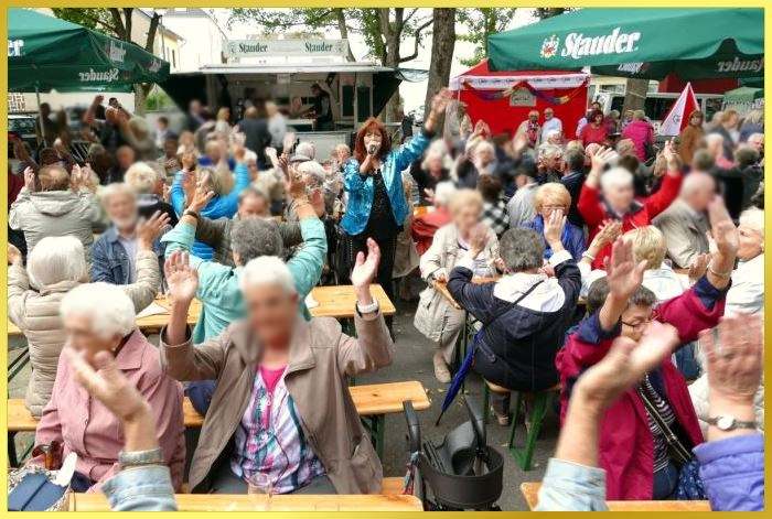 Gro�er vollbesetzter Platz mit Senioren. Marina singt.