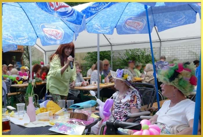 Sommerfest unter bunten Sonnenschirmen. Schlagerpiratin singt.