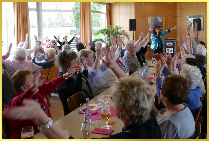 Saal voller feiernder Senioren. S�ngerin animiert zum mitmachen.