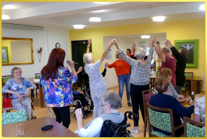 Marina singt, G�ste tanzen und haben die Arme hoch.