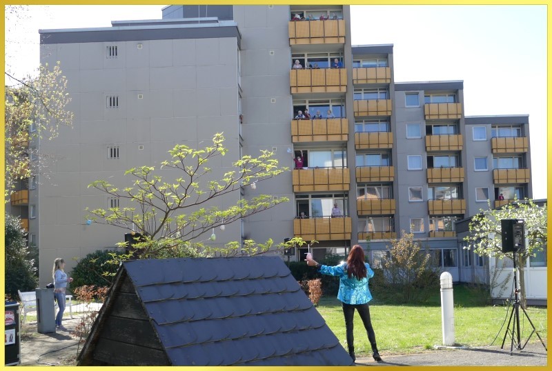 Schlagerpiratin schunkelt singend vor dem Wohnblock