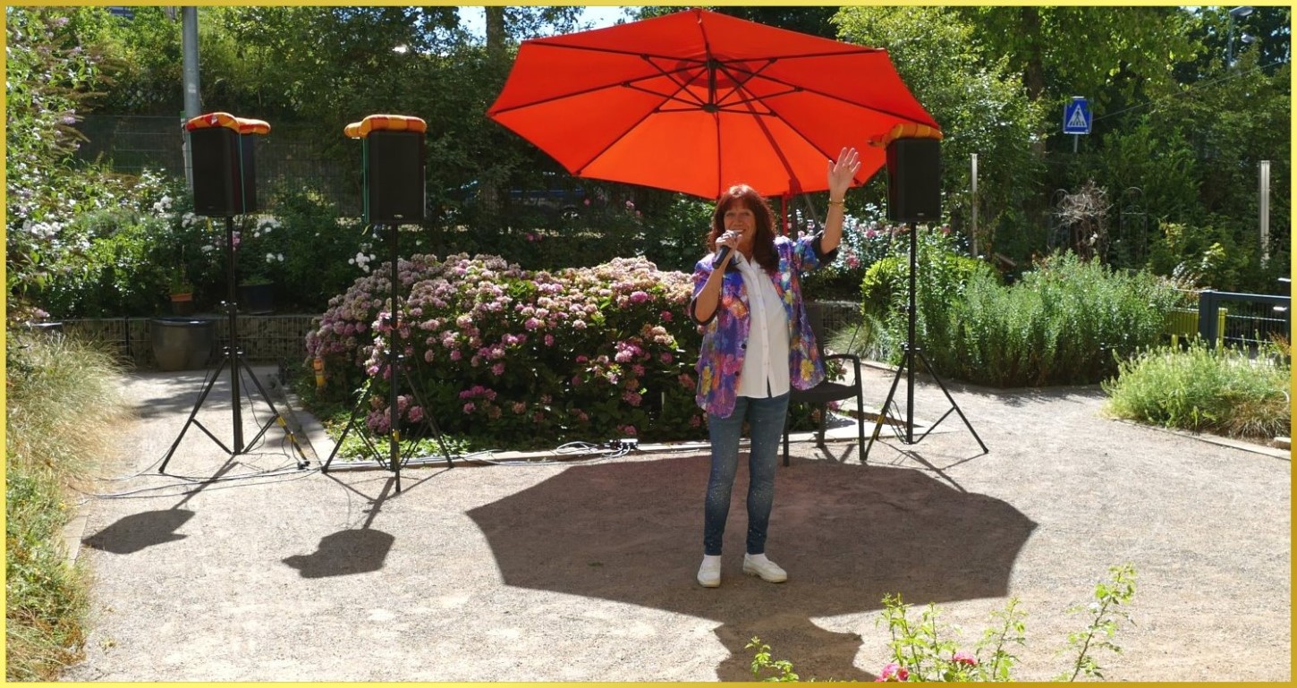 Schlagers�ngerin steht unterm Sonnenschirm und singt