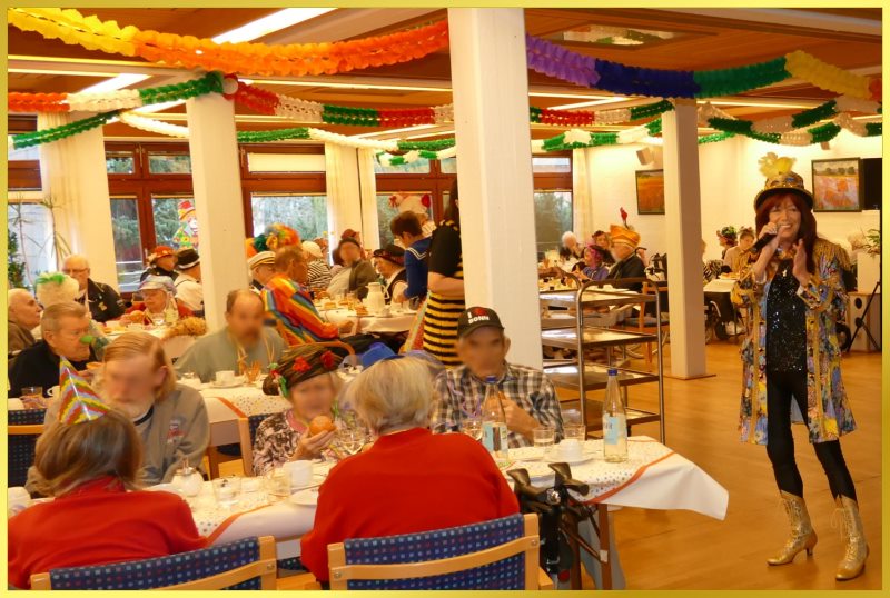 Saal bunt gekleideter Menschen, die Berliner essen.