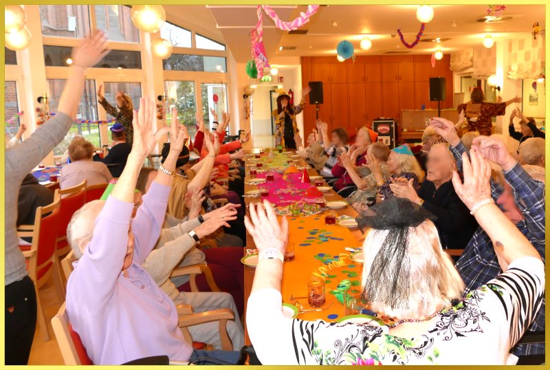 Langer Tisch voller Karnevalsjecken, die winken.