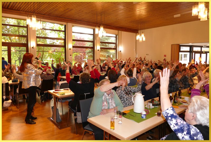 Gro�er Saal voller Frauen, die winken. Marina singt.