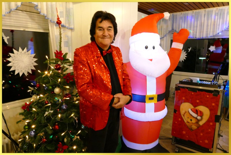 Schatzi Ian steht am Weihnachtsbaum und l�chelt.