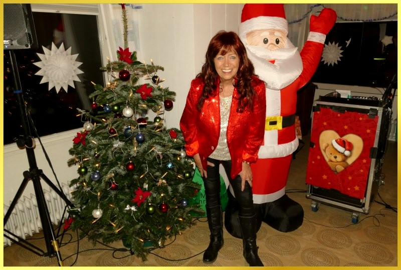 Die Schlagerpiratin steht neben dem Weihnachtsbaum und lacht.