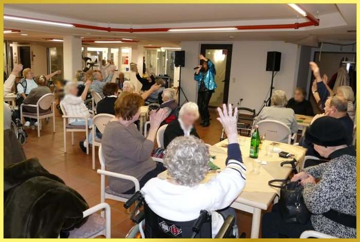 Saal voller Senioren. Schlagerpiratin animiert H�nde zum Himmel.