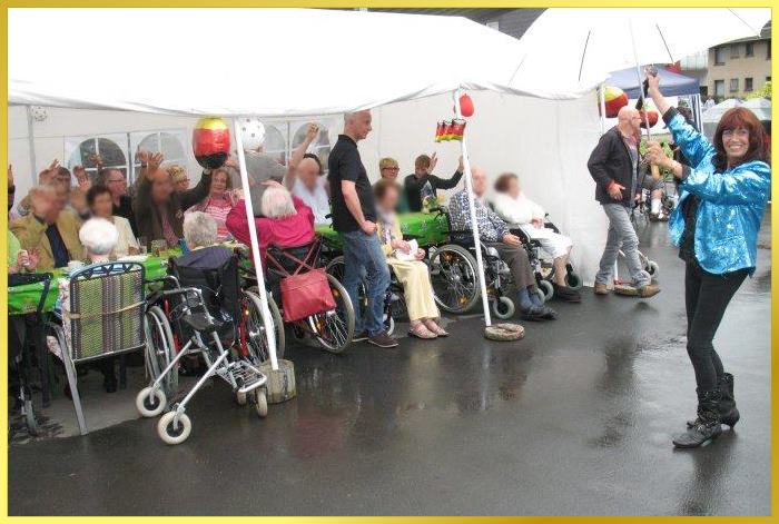 S�ngerin die lacht, singt im Regen. Eine Hand das Mikro, andere Hand der Regenschirm. Lustig!