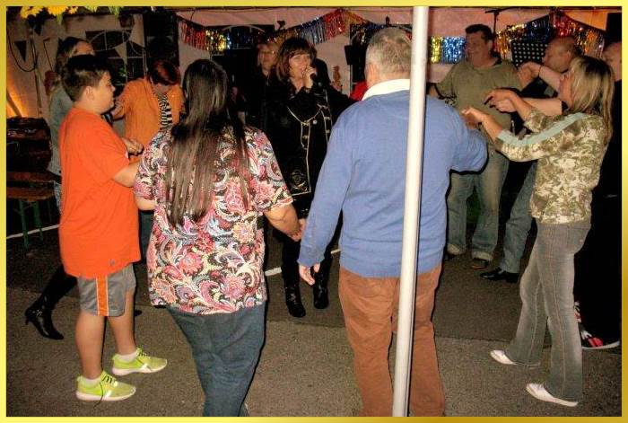 Marina singt. Partyg�ste stehen im Kreis drumherum und schunkeln.