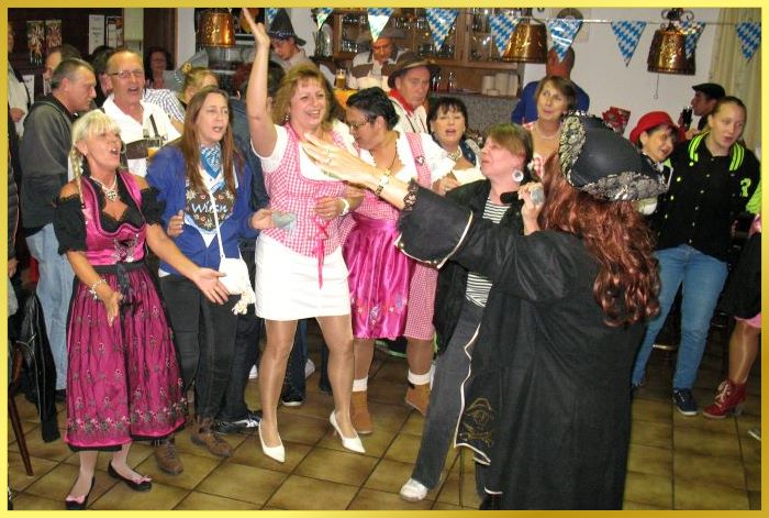 Fr�hliche Partyg�ste stehen vo der Schlagers�ngerin und singen mit.