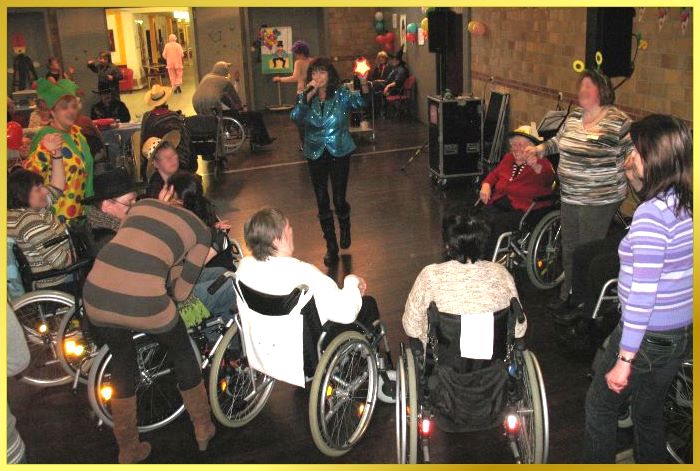 Schlagerpiratin Marina singt EIN STERN und einige Rollstuhlfahrer haben sich im Halbkreis aufgestellt.