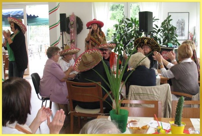 Die Sngerin mit Poncho und Sombrero beim mexikanischen Seniorennachmittag. Auch die Gste tragen Sombreros.