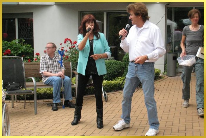 Marina und Ian singen zusammen und sehen sich schmunzeld dabei an.