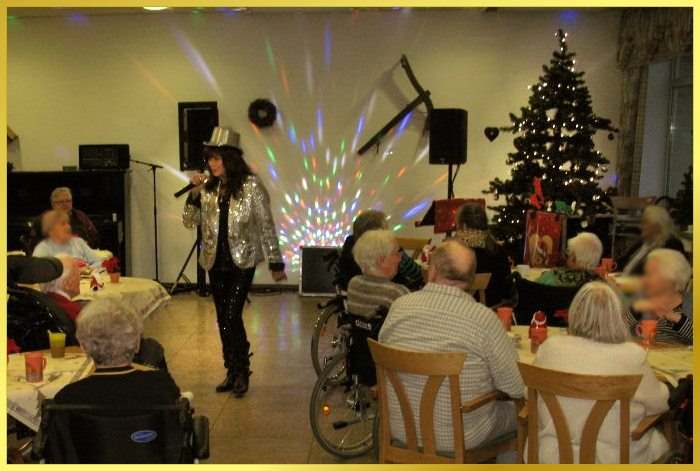 Weihnachtlicher Saal mit Tannenbaum. Schlagers�ngerin mit silbernem Hut und Jacke singt.