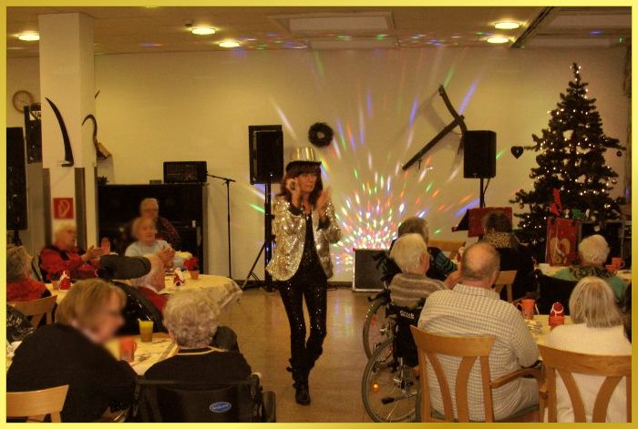 Schlagerpiratin mit silbernem Zylinder, Paillettenjacke singt und klatscht f�r Senioren.