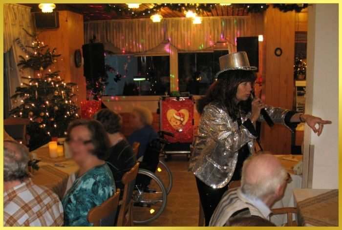 Schlagerrevue zur Weihnachtsfeier mit silbernem Zylinder und Paillettenjacke.