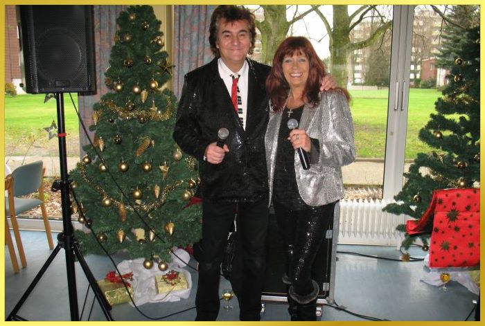 Ian und Marina im Glitzerlook zwischen 2 geschm�ckten Tannenb�umen.