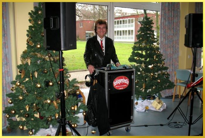 Ian zwischen zwei Weihnachtsb�umen hinter dem Mischpult.