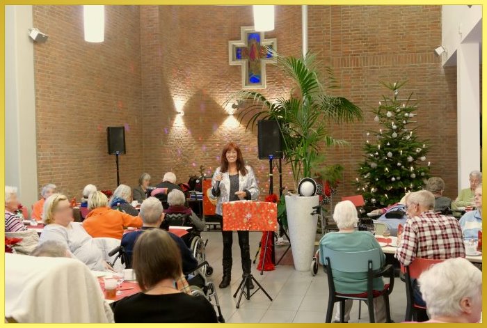 Die Schlagerpiratin singt Weihnachtslieder. Im Hintergrund gro�es farbiges Kreuz an der Wand.